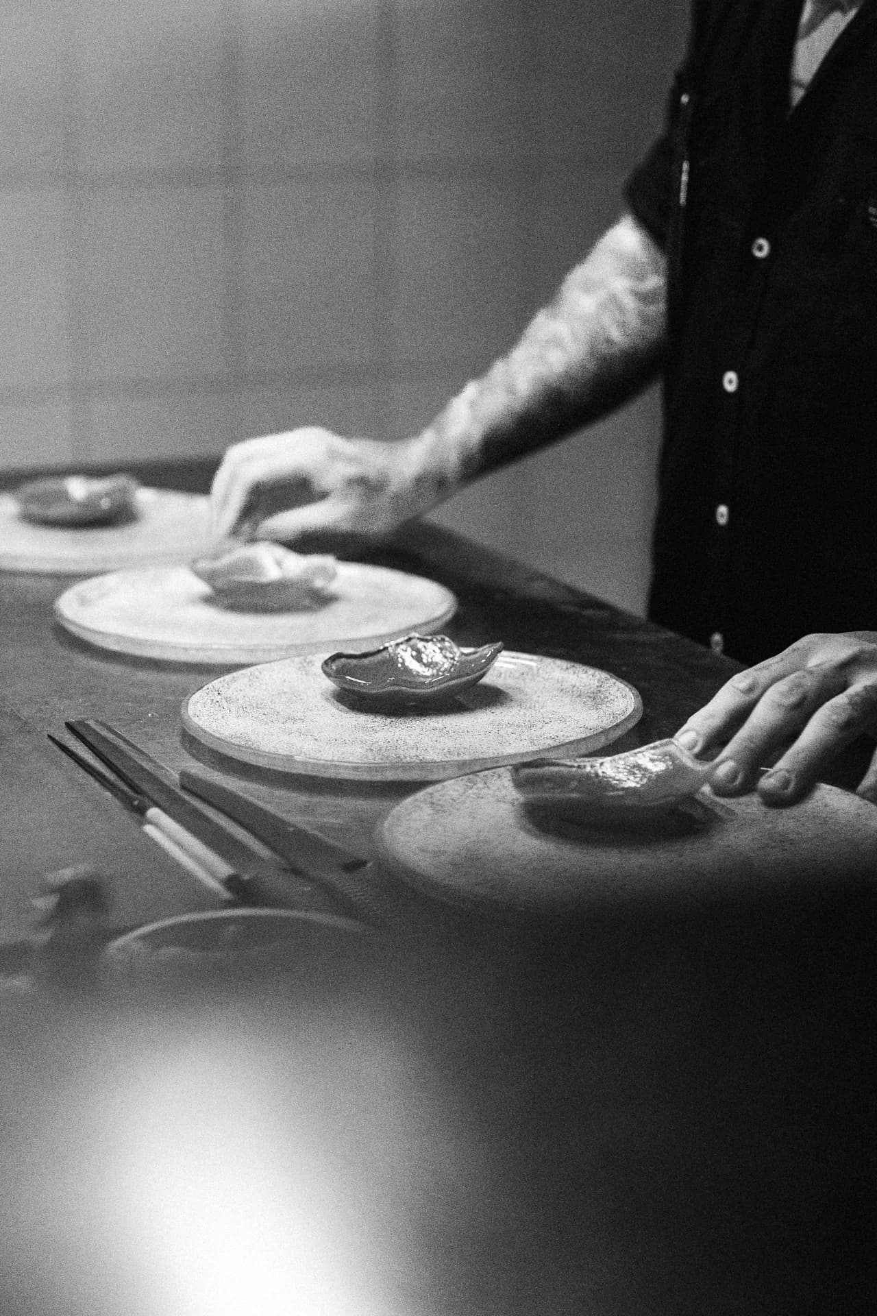 Mains d'un chef dressant des assiettes en cuisine