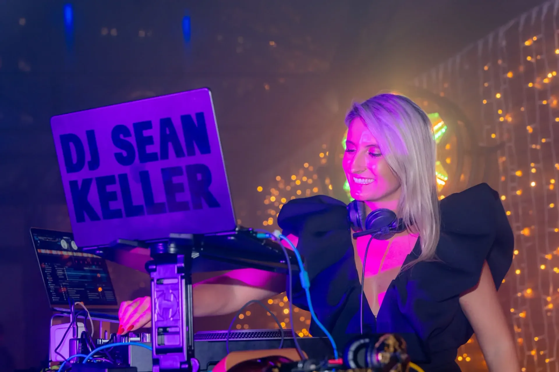 Smiling DJ at the decks during the Gebr. Heinemann Connect & Celebrate evening in Cannes, fairy lights behind, gala evening photo report.
