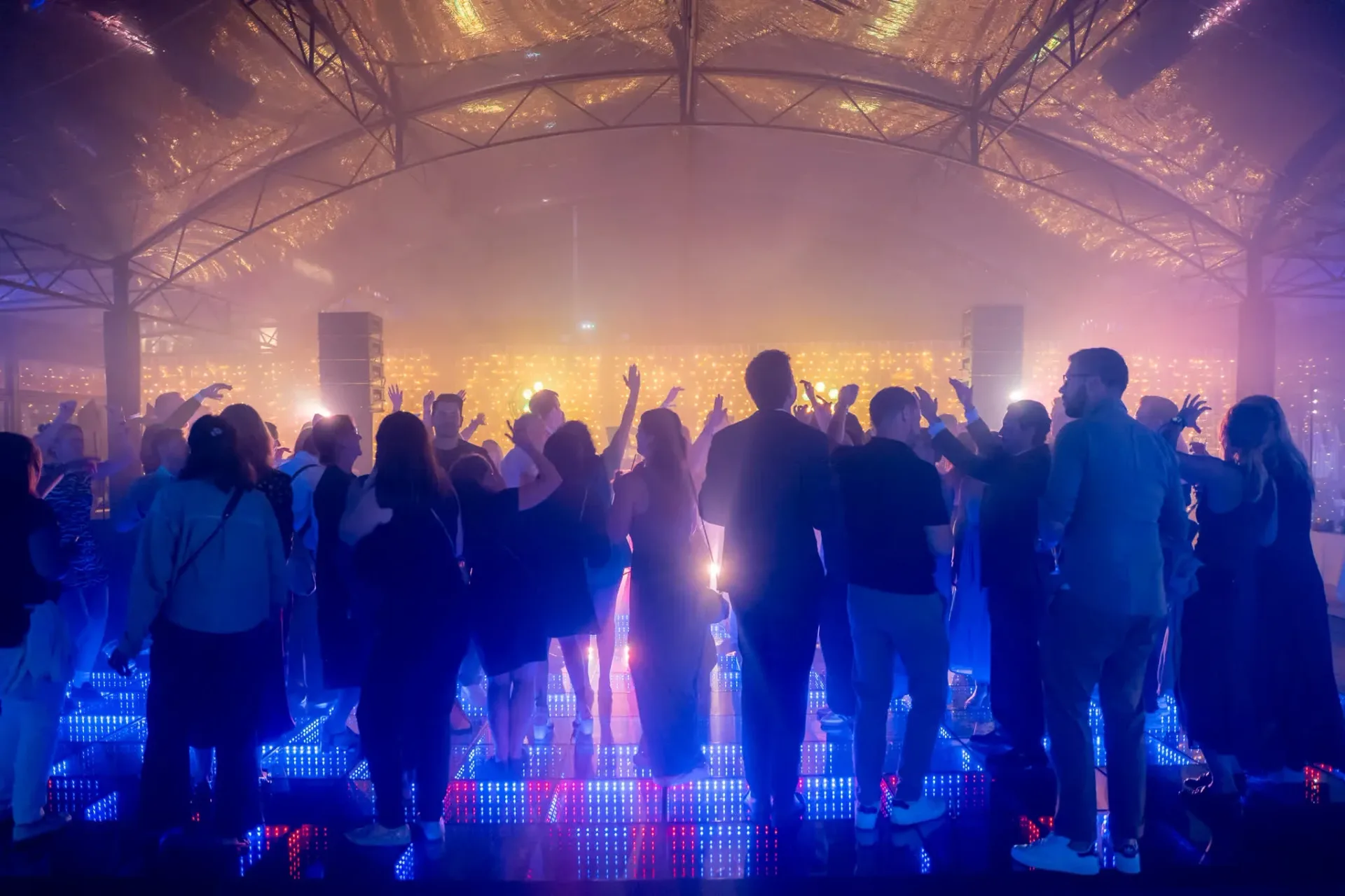 Guests with arms raised on the glowing dance floor, late into the Heinemann gala evening in Cannes, night event photo report.