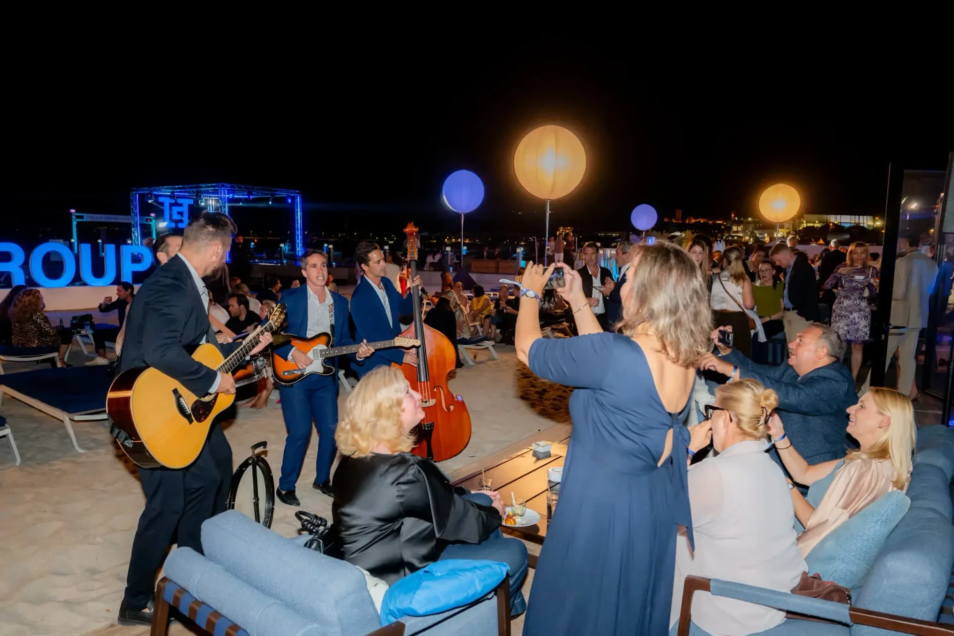 A guest films the musicians with her phone on the beach, friendly atmosphere at the Heinemann gala evening in Cannes, corporate event photo report.