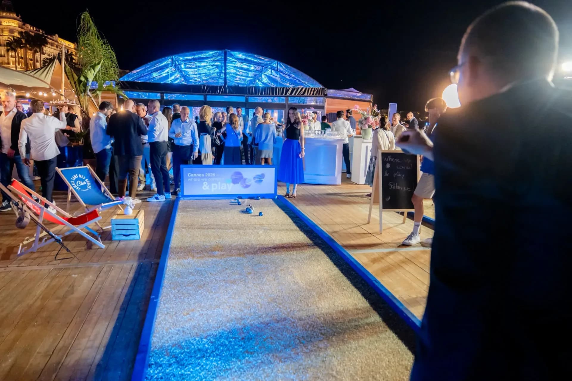 Boules court on the beach deck, Connect & Play area of the Heinemann gala evening in Cannes, with the blue-lit glass roof in the background.