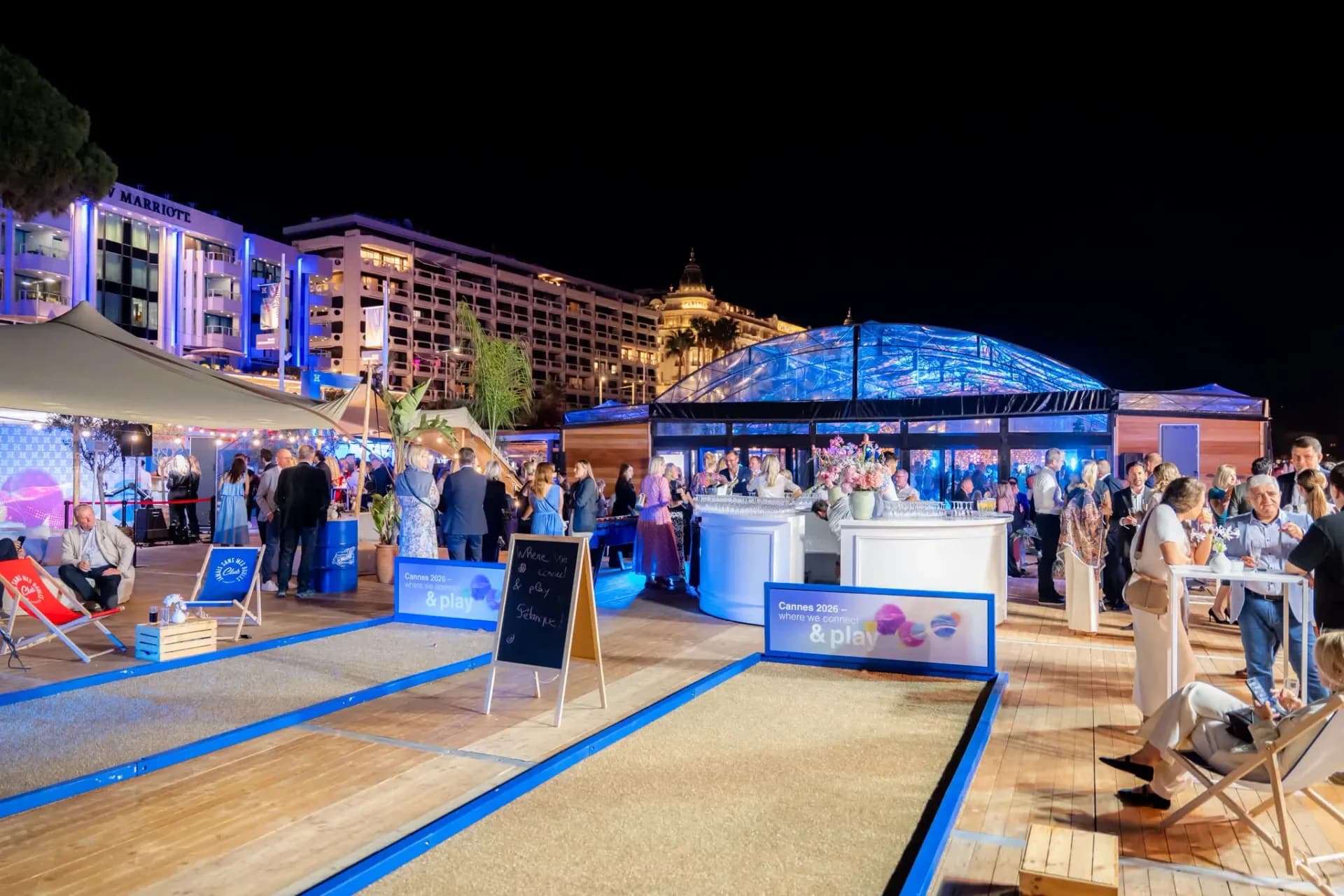Two boules courts facing the Croisette in Cannes, Connect & Play area, Heinemann guests at the bar with the blue glass roof behind.