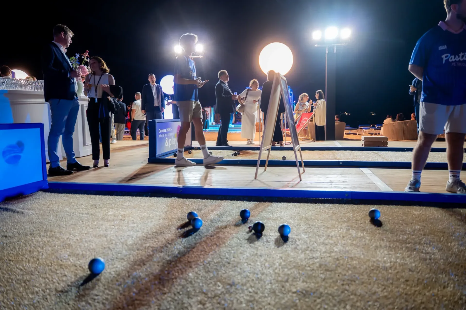 Boules de pétanque sur le sable de la piste Connect & Play, invités en pleine partie lors de la soirée de gala Heinemann à Cannes.