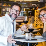 couple-souriant-verres-vin-rouge-restaurant-marbre