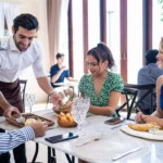 serveur-presente-plat-groupe-amis-restaurant-lumineux