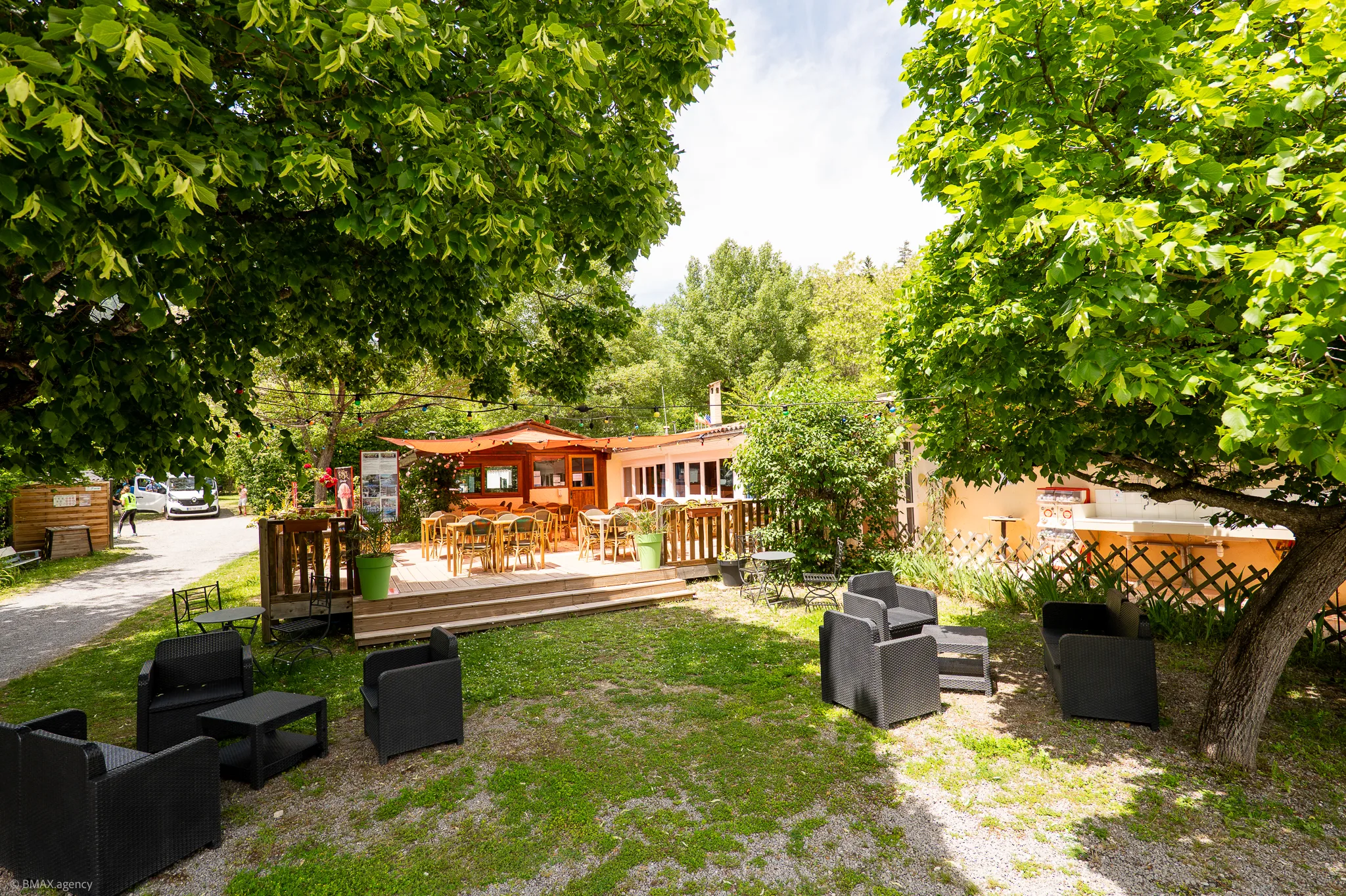 Terrasse extérieure aménagée du bar du camping La Ribière avec fauteuils
