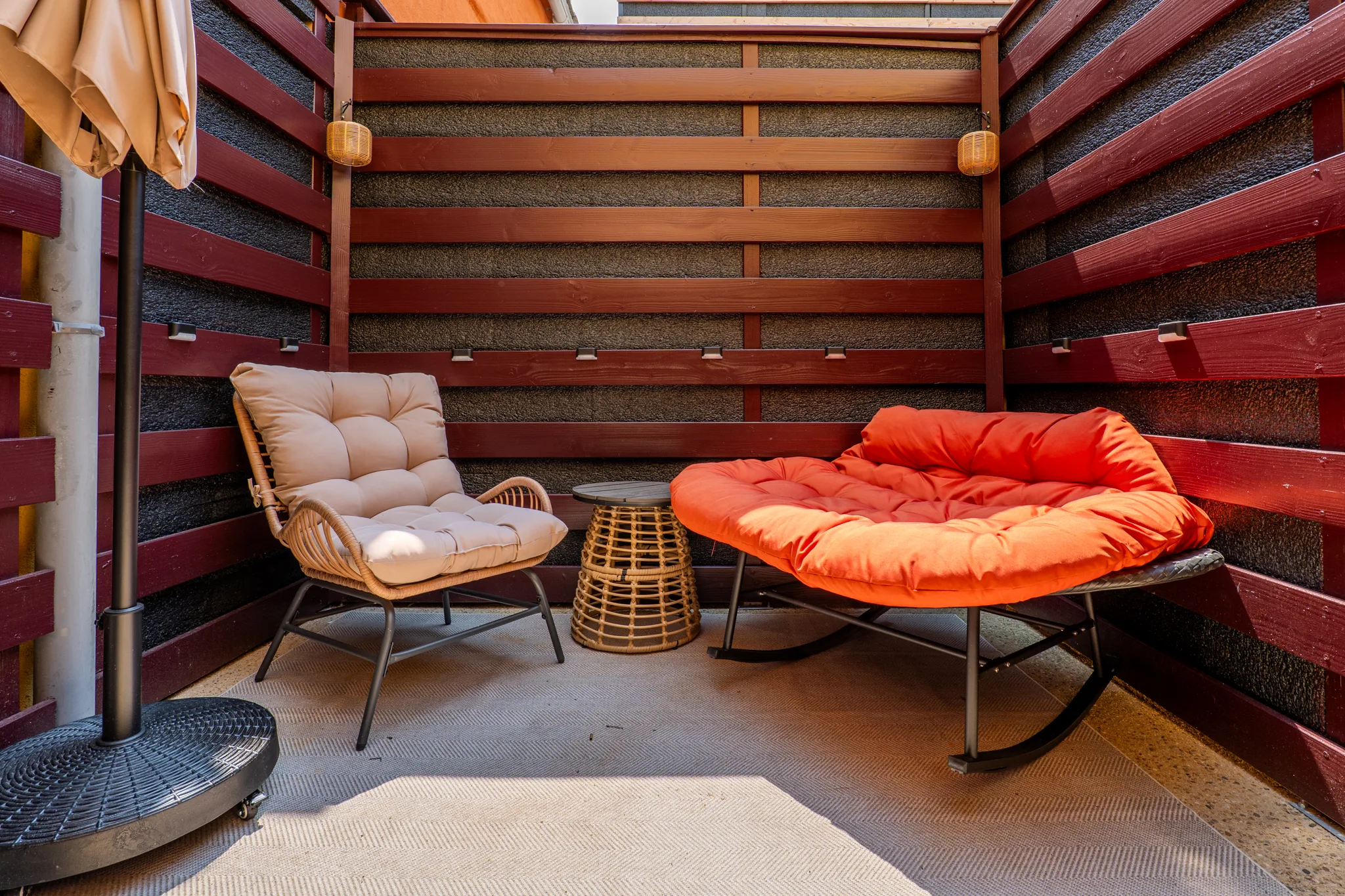 Coin lounge extérieur avec fauteuils rotin et assise ronde orange, ambiance chaleureuse à Manosque.