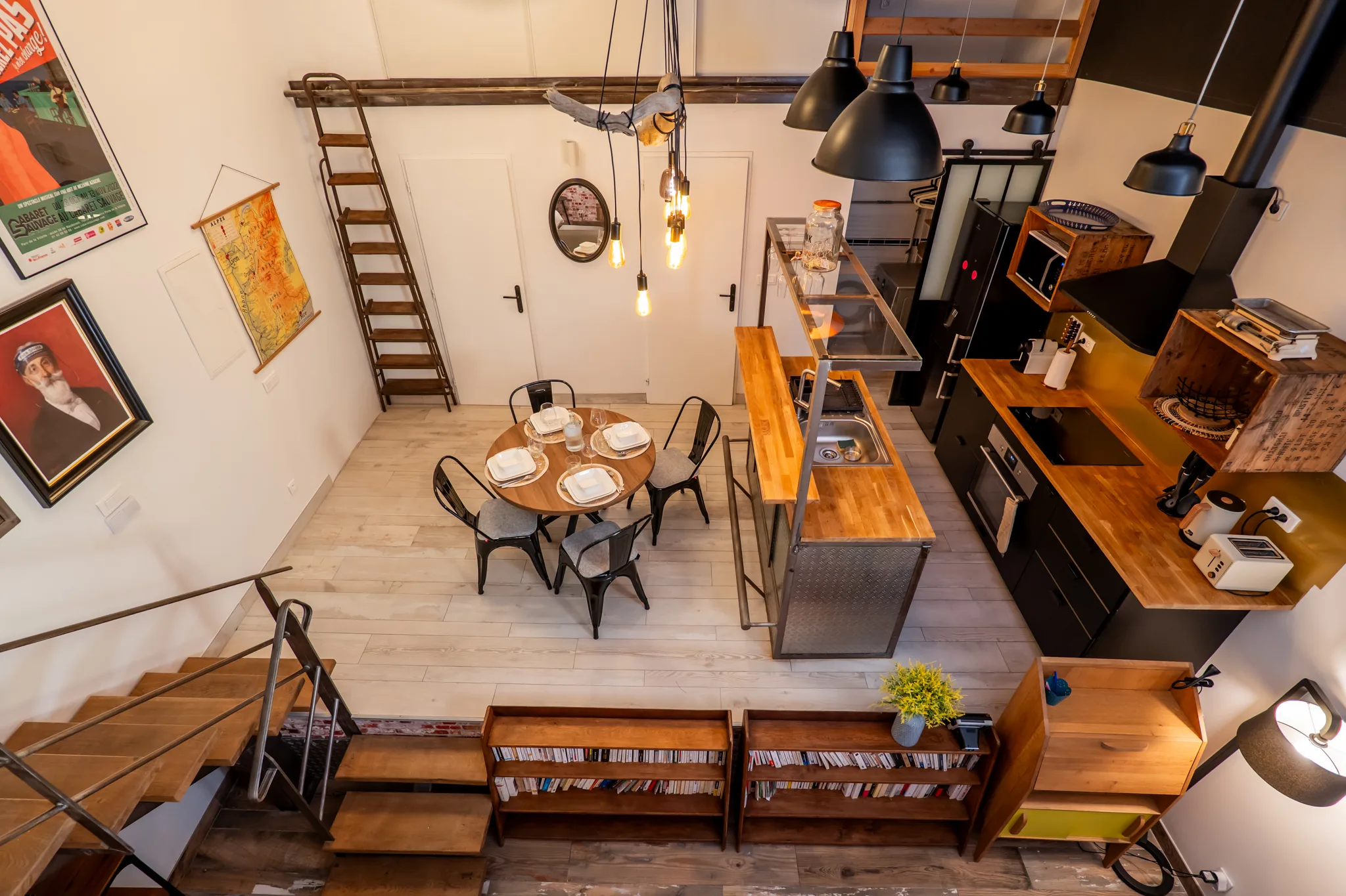 Cuisine et salle à manger vues depuis la mezzanine, avec suspensions industrielles et déco chinée.