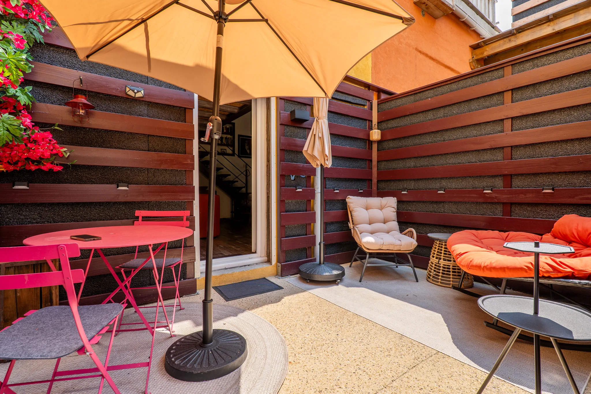 Terrasse extérieure de l'appartement à Manosque avec parasol et mobilier design coloré.